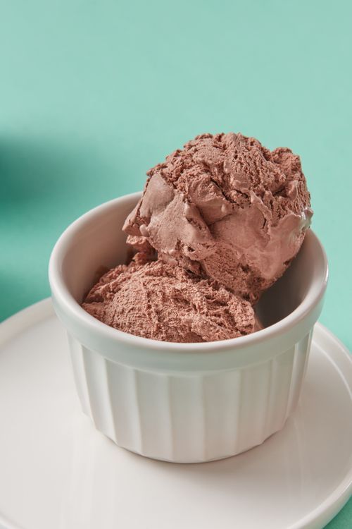 Free Close-up of rich chocolate ice cream in a white ramekin against a teal background. Stock Photo