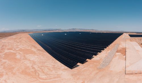 Free Aerial view of a large solar farm in a desert setting under a clear blue sky. Stock Photo