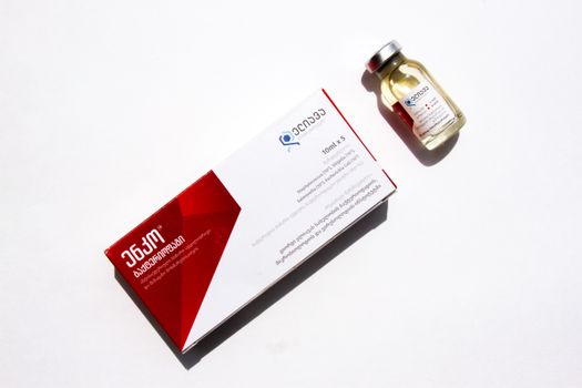 High-angle view of medicine box and vial on a white background with Georgian text.