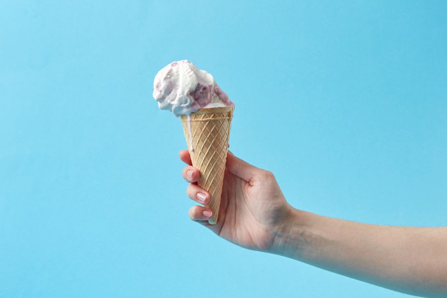 Hand holding a berry swirl ice cream cone
