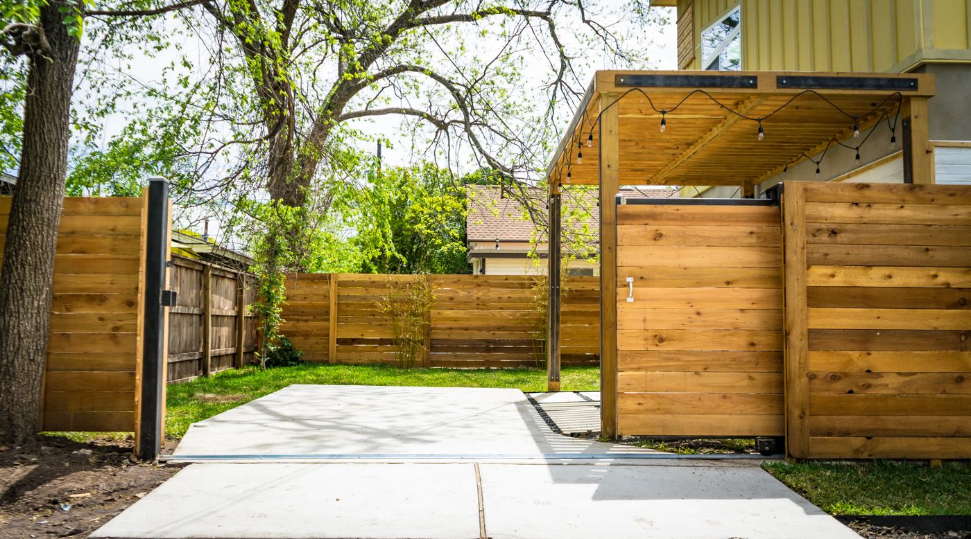 Sunlit wooden backyard fence with a matching gate beside a patio