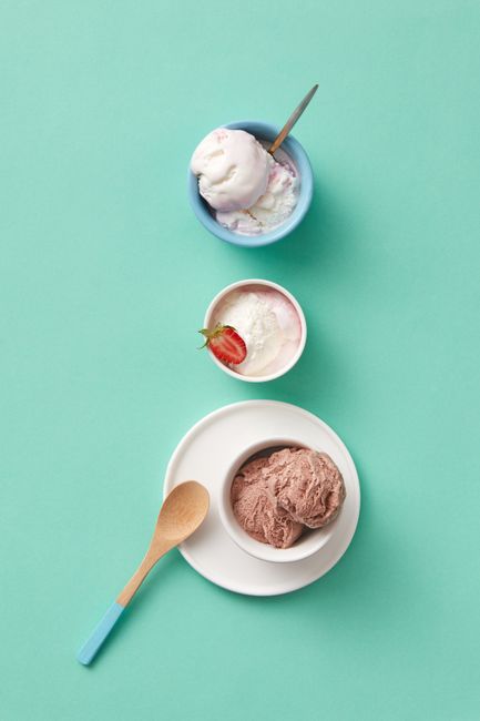 A bowl of creamy pale ice cream made from Greek yogurt, topped with a scoop showing its smooth texture, next to an ice cream scoop.