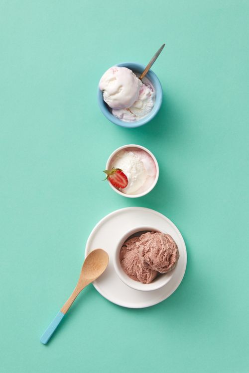 Free Stylish top-down view of chocolate, vanilla, and strawberry ice cream served in bowls with wooden spoon. Stock Photo
