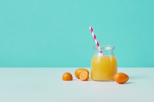 Orange Juice in Clear Glass Jar With Straw