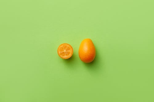 Photograph of a Kumquat on a Green Surface
