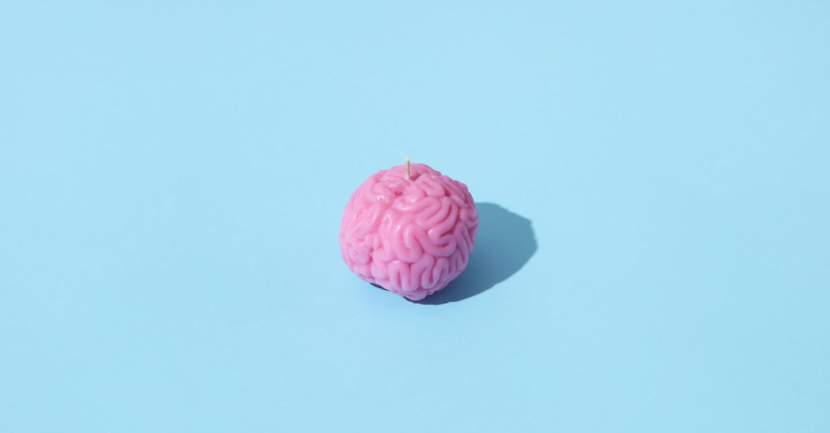 Pink brain-shaped candle on a light blue background, casting a shadow.