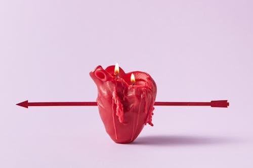 Free Photo of a Red Heart Candle Pierced by an Arrow Stock Photo
