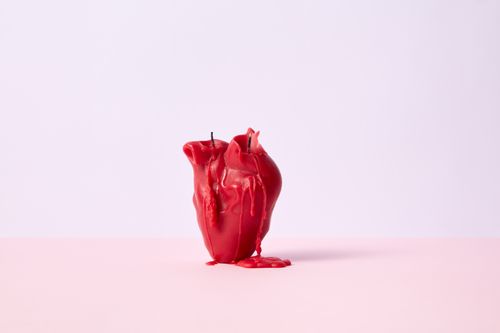Free Close-up of a melted red candle on a pink pastel background, showcasing an artistic design. Stock Photo