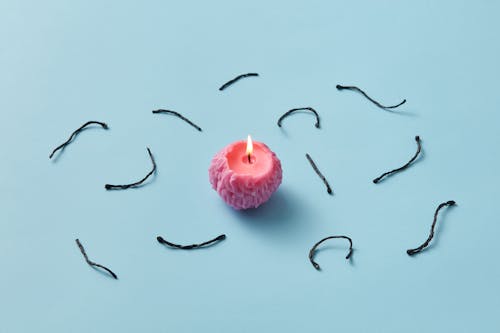 Studio Shot of a Burning Candle Surrounded by Burnt Wicks