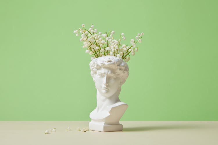 Head Statue With Flowers On Studio Background