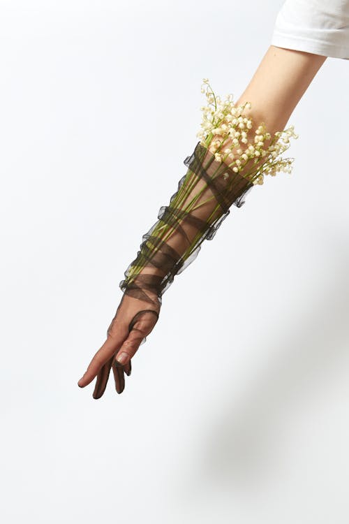 Photograph of a Person's Arm Wrapped with Lily of the Valley Flowers