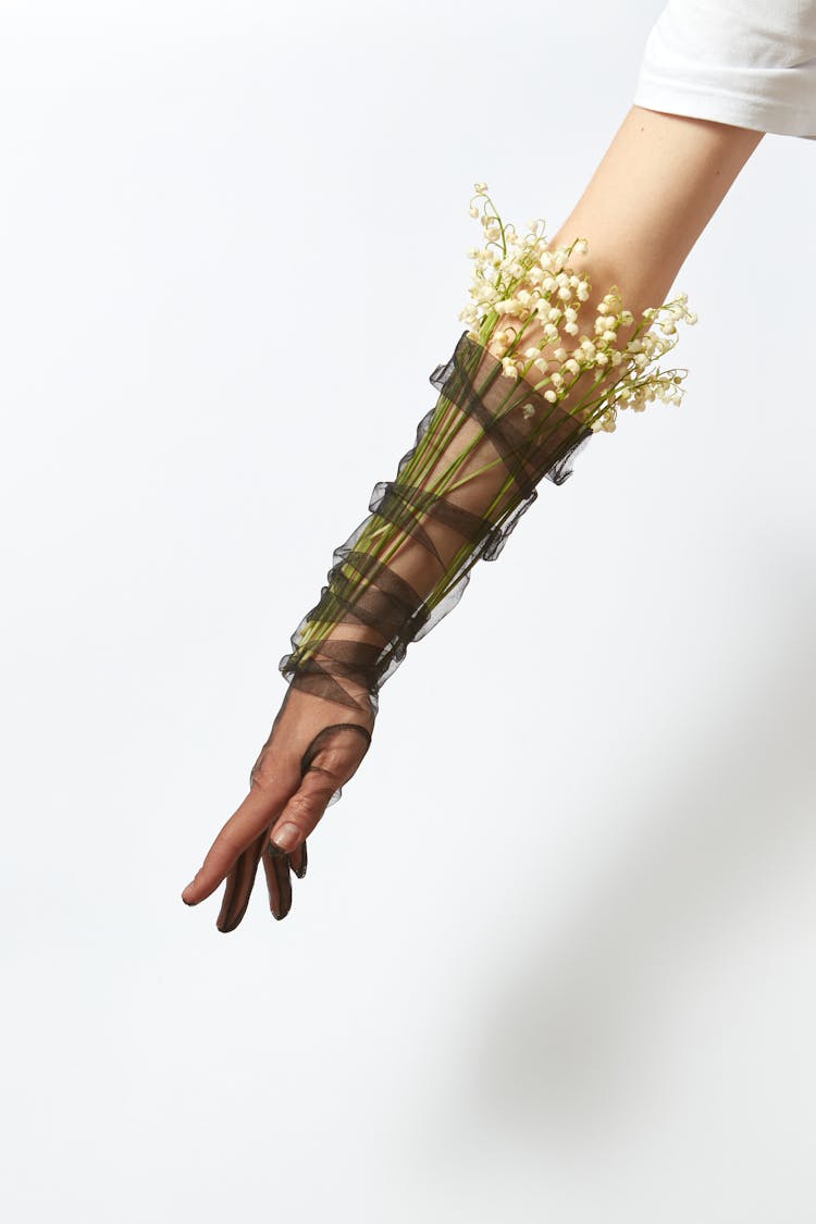 Photograph Of A Person's Arm Wrapped With Lily Of The Valley Flowers