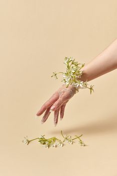 A lace-gloved hand with delicate white flowers on a warm yellow background.
