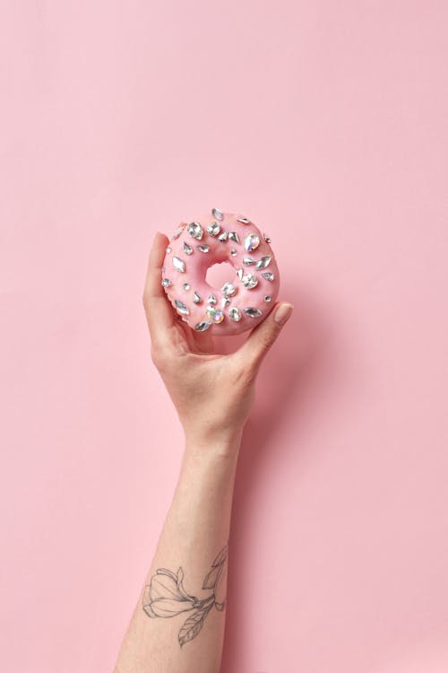 Photo of a Person's Hand Holding a Donut with Diamonds