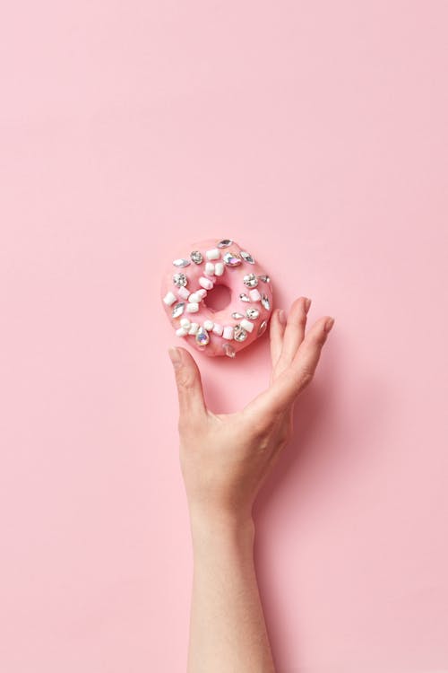 Photo of a Person's Hand Getting a Donut with Diamonds