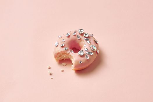 A donut with pink glaze and diamond decorations, showcasing luxurious style on a soft pastel background.