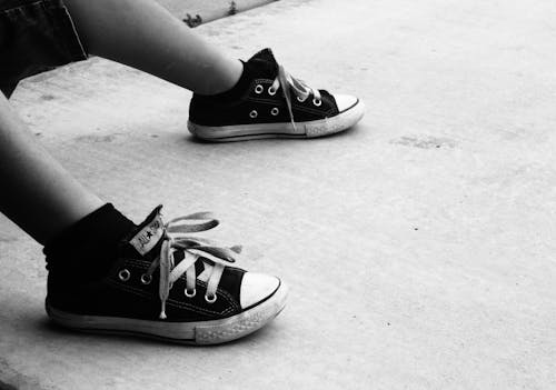 Grayscale Photo of a Person Wearing Converse Shoes