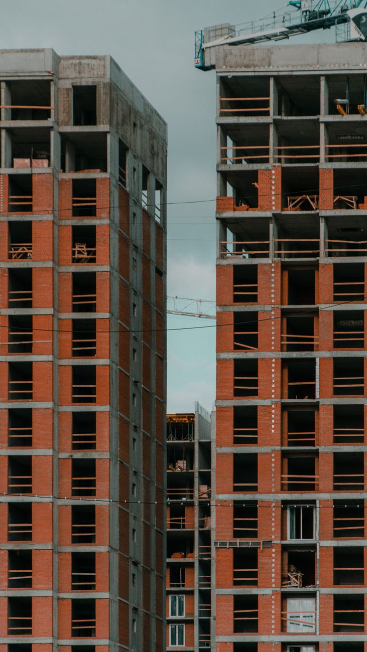 Vertical shot of partially constructed skyscrapers with cranes overhead.