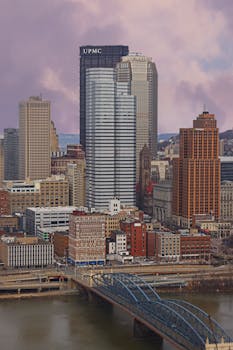 A vibrant aerial view of downtown Pittsburgh highlighting its iconic skyscrapers and river bridge.