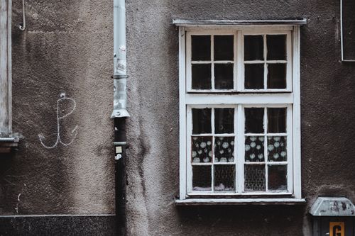 Free Close-up of a vintage window set in an aged, graffiti-marked wall, showcasing urban decay and architectural textures. Stock Photo