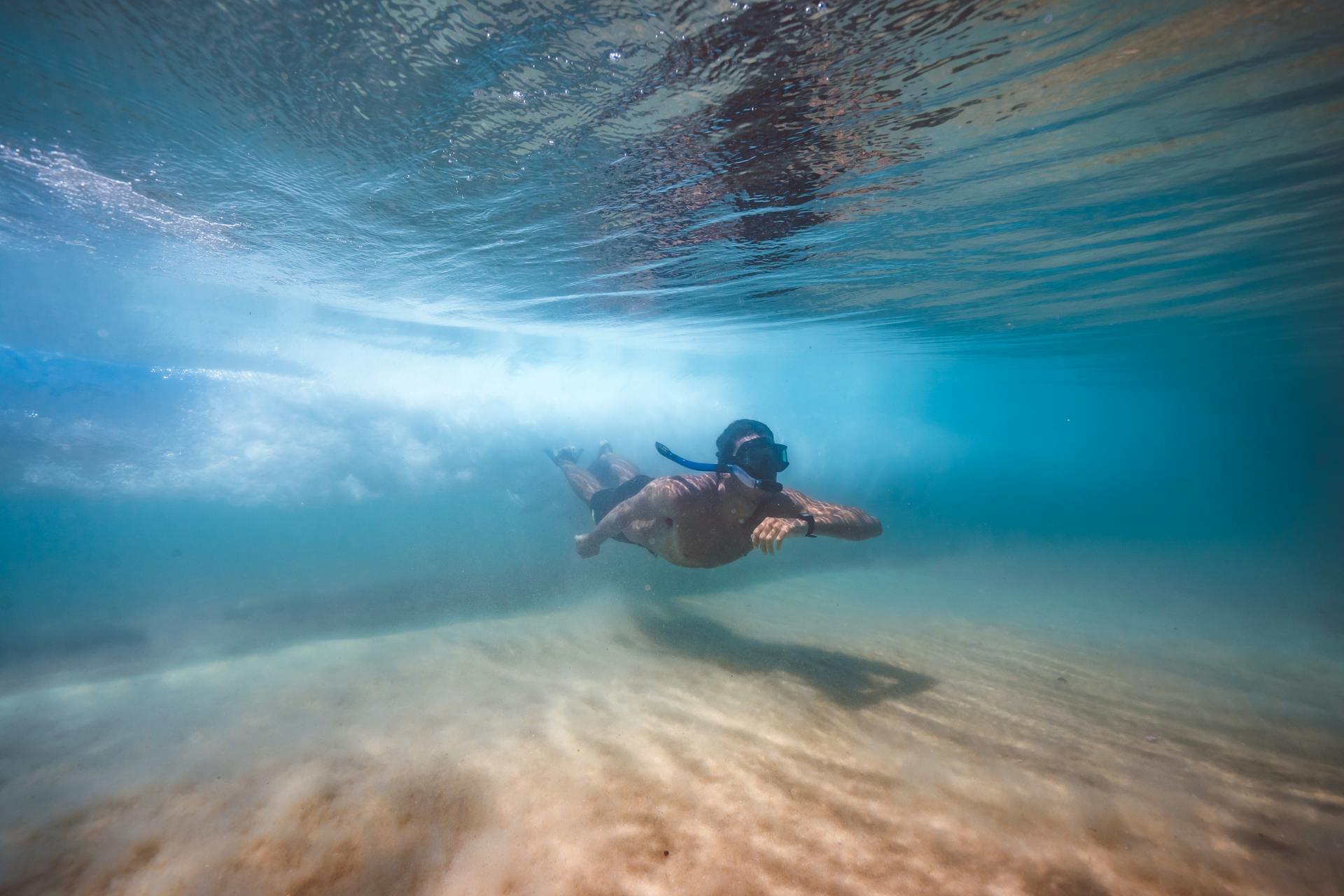 A man enjoys snorkeling in pristine, clear waters, showcasing underwater adventure and marine exploration.