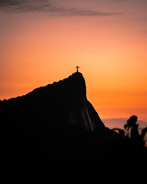 Free Silhouette of Christ the Redeemer against a vibrant sunset in Rio de Janeiro, Brazil. Stock Photo
