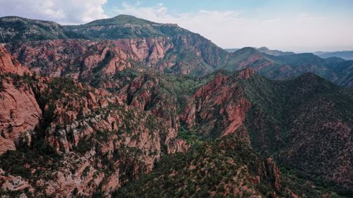 Free Captured a stunning aerial view of rugged red and green mountain ranges under a clear sky. Stock Photo