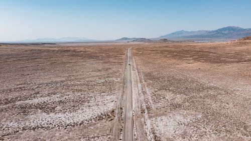 Free Aerial view of a straight desert road stretching through a vast barren landscape. Stock Photo