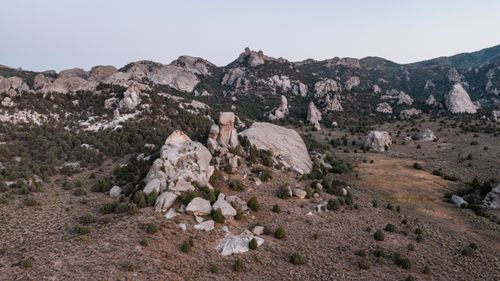 Free Drone view of rugged rocky mountains and scattered greenery during dusk, showcasing nature's raw beauty. Stock Photo