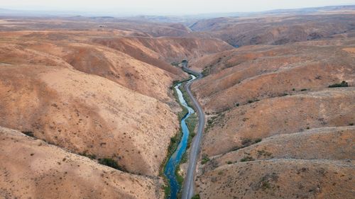 Free Aerial shot of a desert valley with a winding river and road, showcasing natural beauty. Stock Photo