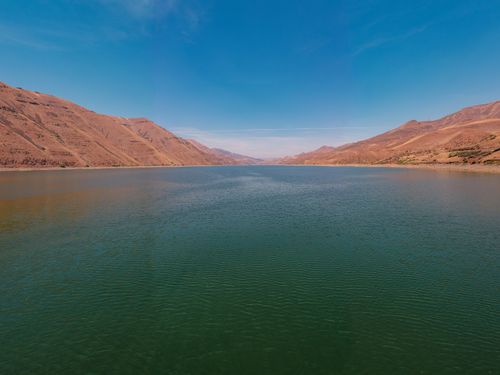 Free Breathtaking view of a tranquil lake surrounded by arid mountains under a clear blue sky. Stock Photo