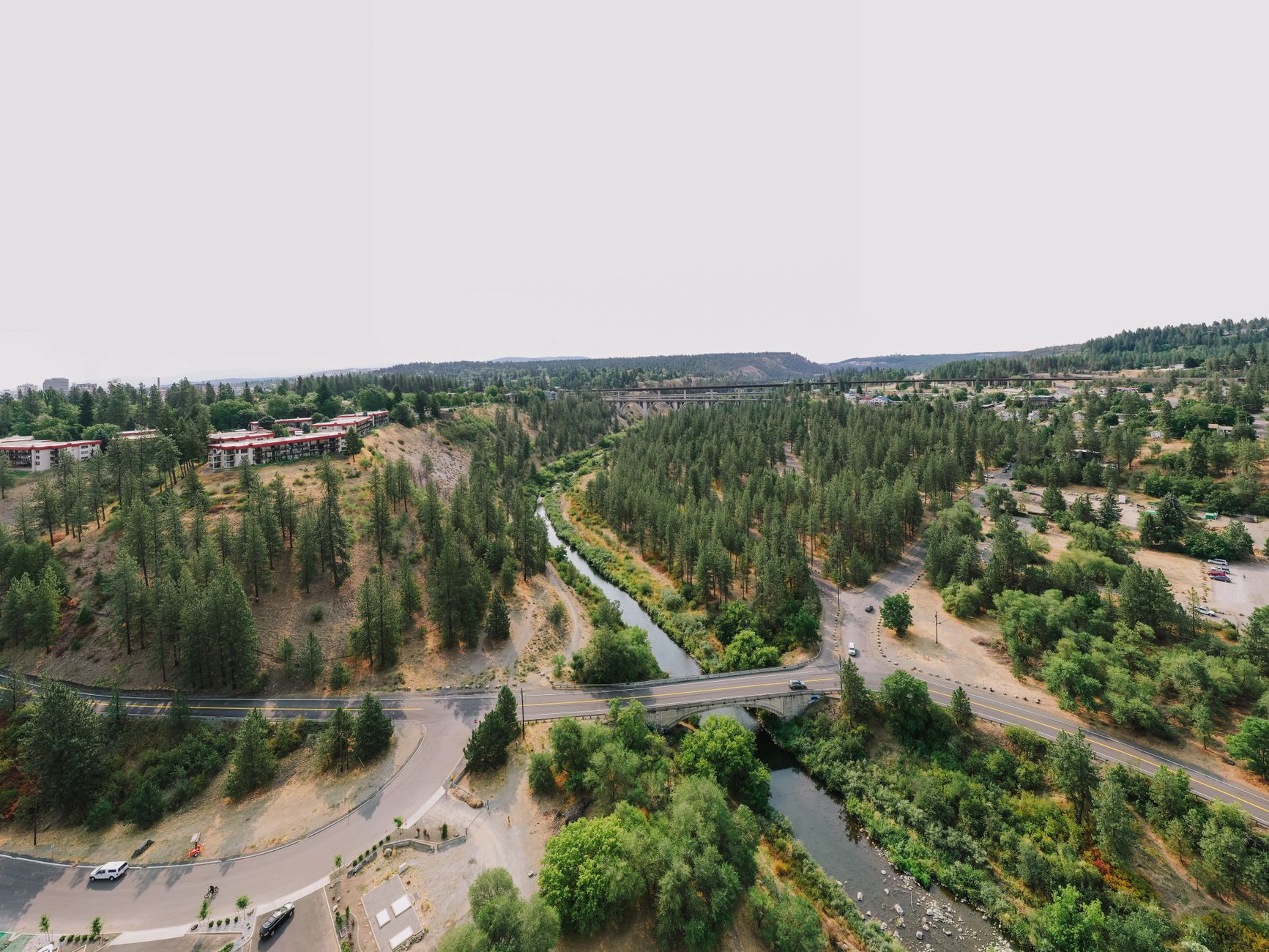 Aerial view showcasing a bridge over a winding river surrounded by lush green forest.