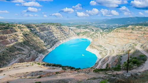 Free A heart-shaped lake with vibrant blue water surrounded by rocky cliffs under a cloudy sky. Stock Photo
