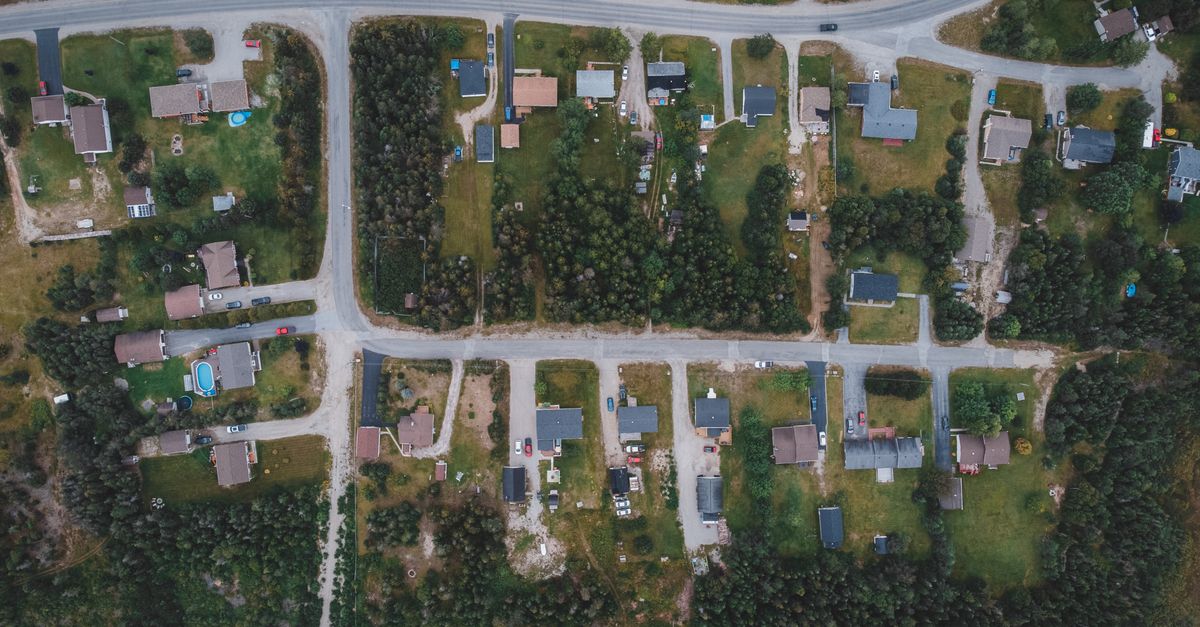 Aerial photo capturing a suburban neighborhood layout with houses, roads, and greenery.