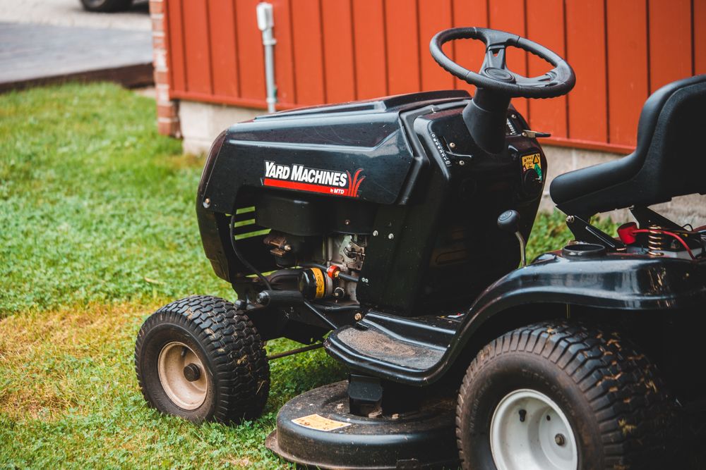 Tondeuse autoportée sur une pelouse, devant un abri de jardin
