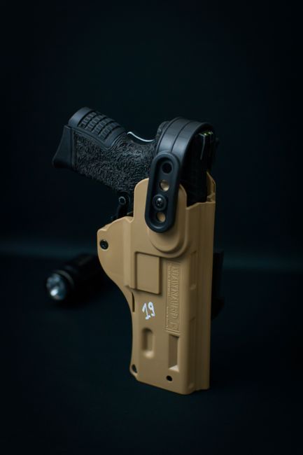 A black handgun secured in a tan holster