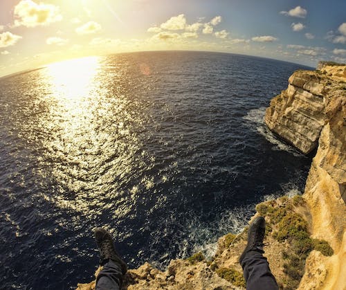 бесплатная Человек на вершине Каменного острова на берегу моря во время заката Стоковое фото