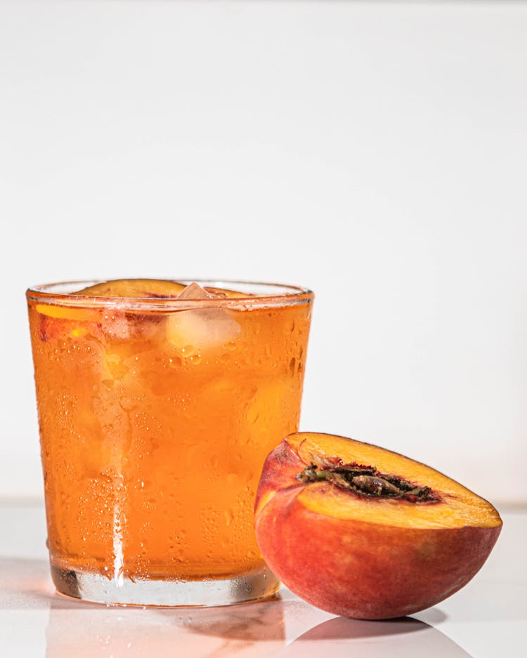 Photo Of A Drink Beside A Sliced Peach