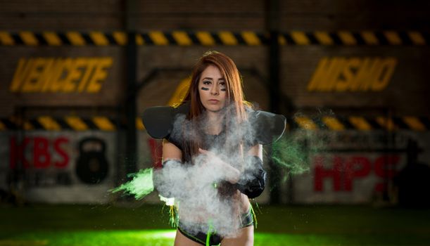 Confident female American football player with smoke effect in sports gear.