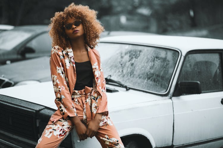 Woman Wearing Brown Floral Print Coat And Pants Sitting On Car