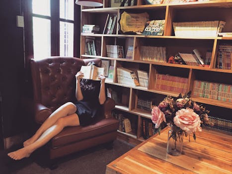 Woman in Black Mini Dress Sitting on Brown Leather Tufted Sofa Chair Beside Brown Wooden Book Shelf