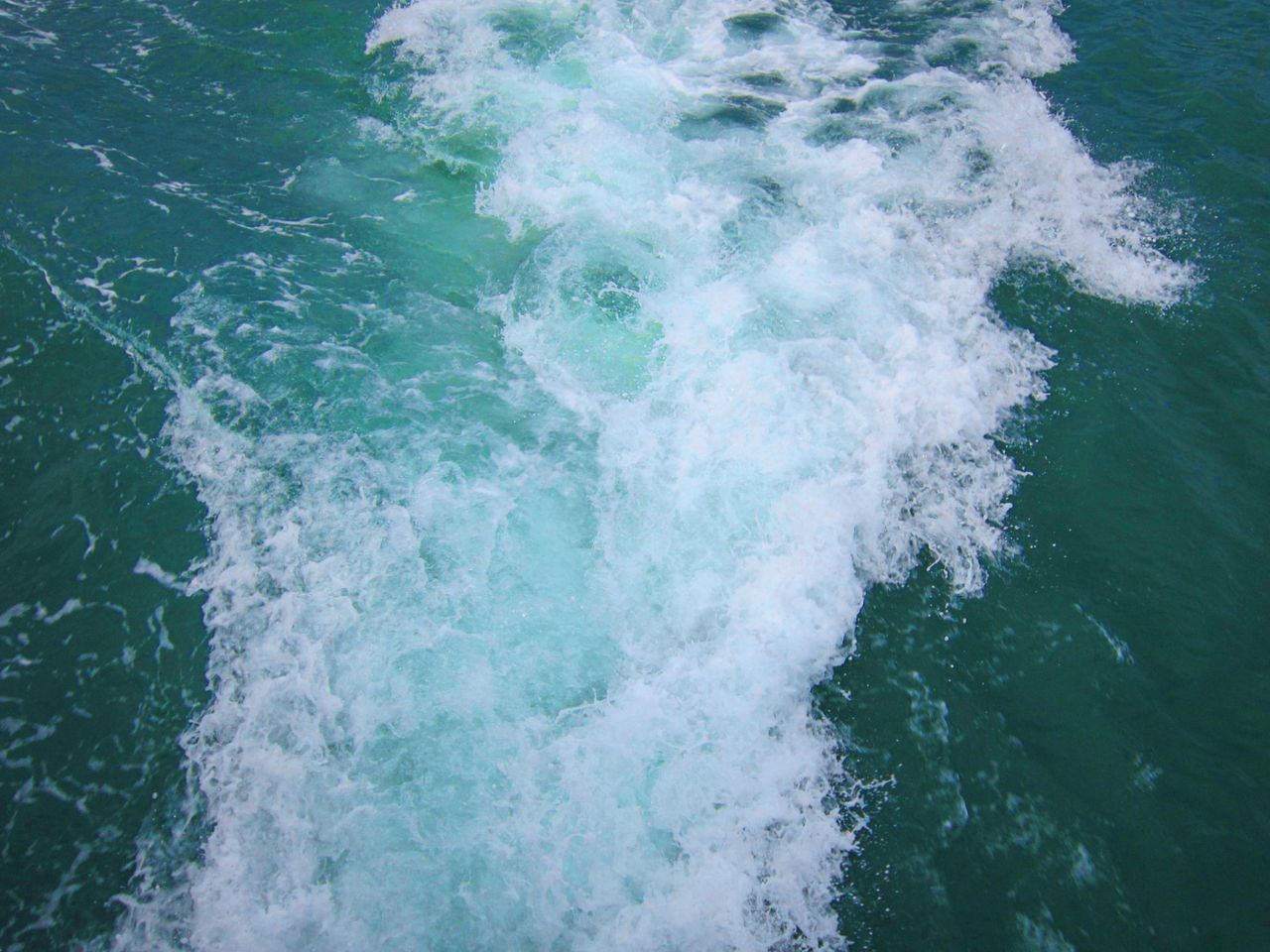 aerial view of turquoise ocean waves crashing with white foam on the s