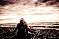 日落时分，一个人在海滩上冥想，头顶是壮观的云层，背景是海浪