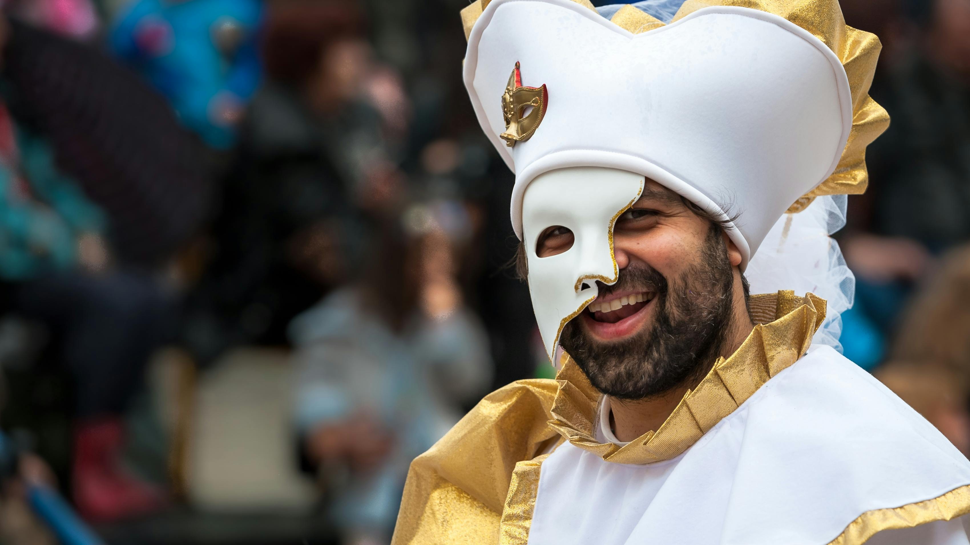 Free A joyful man wearing a carnival mask and costume, enjoying a festive event. Stock Photo