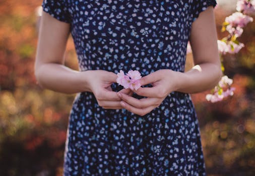 Women in Blue and White Floral Dress With Pink Flower on Hand