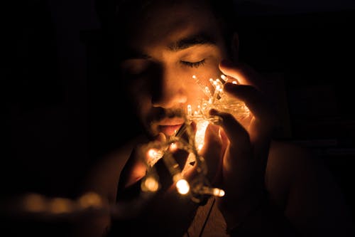 Free Close-up Photography of Man Holding Christmas Lights Stock Photo