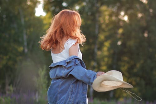 A Woman With a Denim Jacket Holding a Cowboy Hat