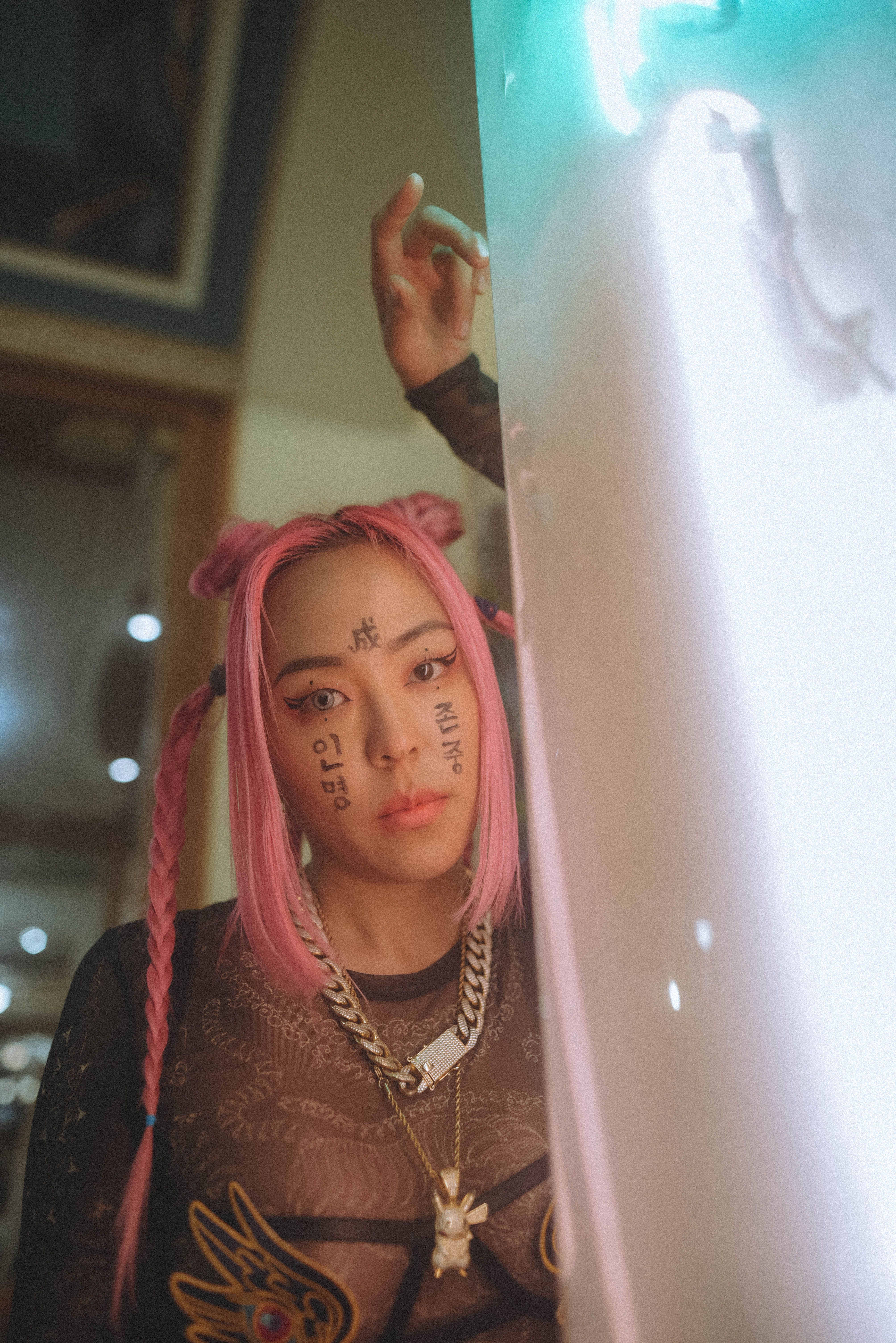 Creative portrait of a young woman with pink hair and artistic face paint, showcasing modern style.