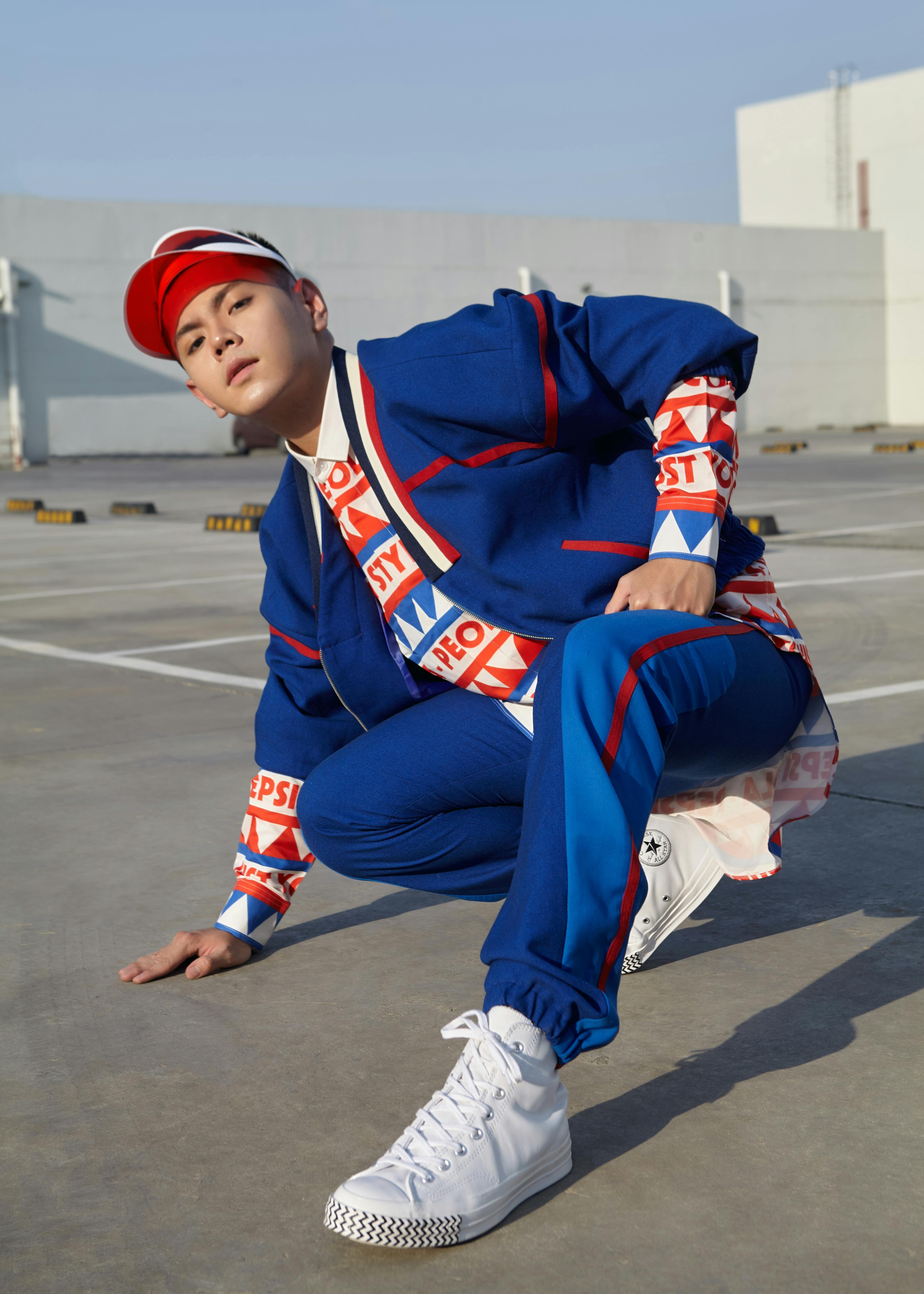 Young man in vibrant attire posing outdoors on a sunny day.