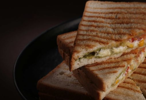 Close-up of a toasted sandwich filled with vegetables and cheese on a plate.